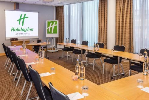 a conference room with tables and chairs and a screen at Holiday Inn Preston by IHG in Preston