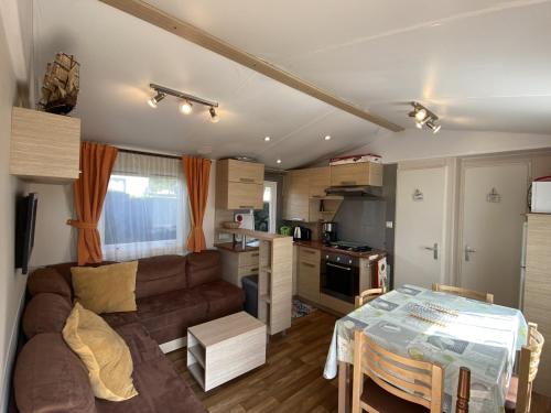 un salon et une cuisine avec un canapé et une table dans l'établissement Mobil-home à Fouras : Proche Plage, 2 Chambres, TV, Plancha, Parking, Idéal Famille - FR-1-709-58, à Fouras