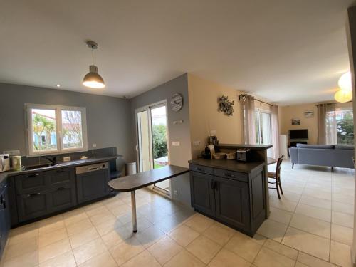 une grande cuisine avec des armoires noires et une table dans l'établissement Villa Confortable à Fouras, Proche Mer, 3 Chambres, Terrasse, Jardin, WiFi - FR-1-709-59, à Fouras