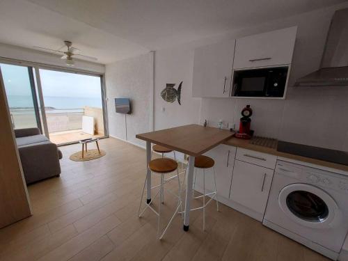 une cuisine avec une table et une machine à laver dans l'établissement Grau d'Agde : Studio cabine avec terrasse, parking privé, vue mer - FR-1-423-270, au Grau-dʼAgde