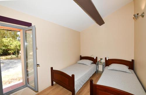 2 camas en una habitación con ventana en Les appartements du Mas Riols, en Saint-Cyprien