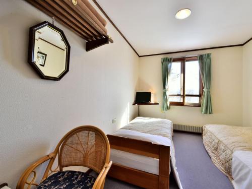 - une chambre avec 2 lits, un miroir et une fenêtre dans l'établissement Kurumayama Kogen Guesthouse Urara, à Chino