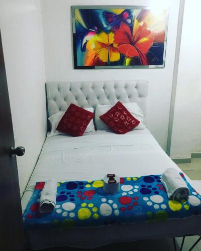 a bed with red pillows and a painting at Costa atlantico in Barranquilla