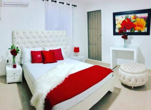 1 dormitorio con 1 cama blanca grande con almohadas rojas en Costa atlantico, en Barranquilla