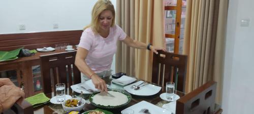 a woman standing over a table cutting a cake at Enara Luxury Stay in Katugastota