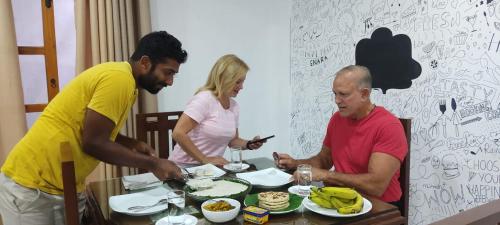 a group of people sitting around a table eating food at Enara Luxury Stay in Katugastota