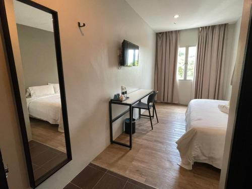 een hotelkamer met een spiegel, een bed en een bureau bij Chariton Hotel Butterworth in Butterworth