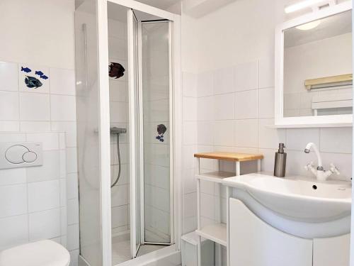 La salle de bains blanche est pourvue d'un lavabo et d'une douche. dans l'établissement Appartement Le Lavandou, 1 pièce, 4 personnes - FR-1-251-491, au Lavandou