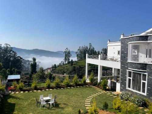 a house with a yard with a table and chairs at Orchard Valley View in Ooty