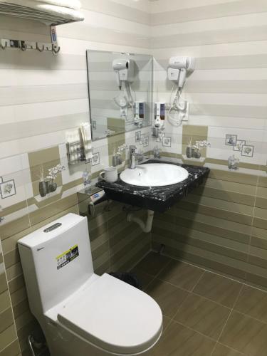 a bathroom with a sink and a toilet and a mirror at Sea Balcony Hotel in Cat Ba