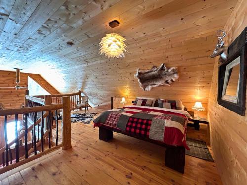 a bedroom with a bed in a log cabin at WAPITI - Chalets de Môh - Jacuzzi in La Malbaie
