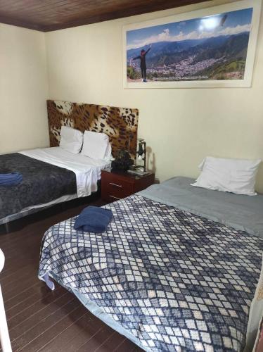 1 dormitorio con 2 camas y una foto en la pared en CASA MUY CONFORTABLE EN ZAMORA CHINCHIPE incluye desayuno, en Zamora