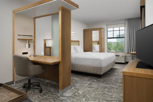 a hotel room with a bed and a desk and a television at Springhill Suites by Marriott Jackson North/Ridgeland in Ridgeland