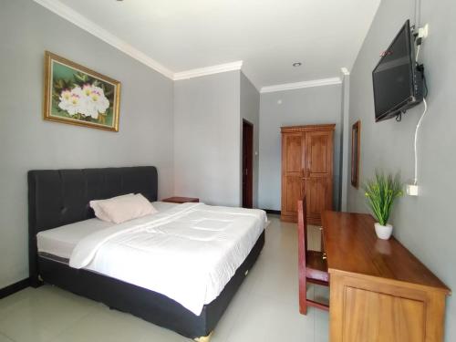 a bedroom with a bed and a flat screen tv at Hotel Asri Baru in Purwokerto