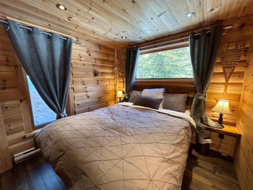 a bedroom with a bed in a log cabin at WOODY - Chalets de Môh in La Malbaie