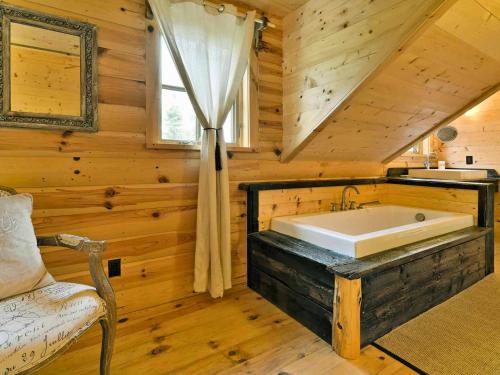 ein Badezimmer mit einer großen Badewanne in einem Blockhaus in der Unterkunft BIGFOOT - Chalets de Môh - Jacuzzi in La Malbaie