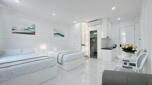 a white hotel room with two beds and a table at PARIS HOTEL in Danang