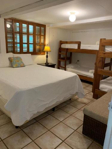 a bedroom with a bed and two bunk beds at Looking Good Surf House San Juan del Sur in San Juan del Sur