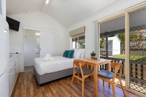 a bedroom with a bed and a table and chairs at Reflections Ballina - Holiday Park in Ballina