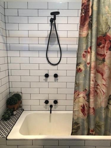 a bath tub with a shower curtain in a bathroom at Goldfields House in Metcalfe