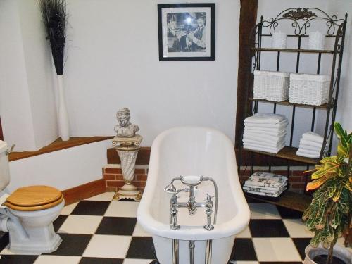 a bathroom with a bath tub and a toilet at Doves Barn in Needham Market