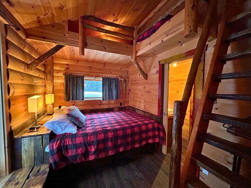 a bedroom with a bed in a wooden cabin at HUSKY - Chalets de Môh - Jacuzzi in La Malbaie