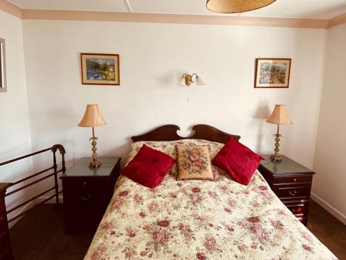 a bedroom with a bed with red pillows and two lamps at Merriview in Germoe