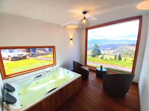 a bathroom with a tub with two chairs and a large window at Bajo las estrellas deluxe in Ráquira