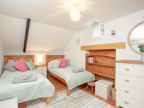 a bedroom with two beds and a mirror at The Coach House in South Zeal