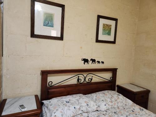 1 dormitorio con 1 cama y 2 cuadros en la pared en Best Relax in the best part of Gozo your own bedroom with Ensuite Toilet and Shared Pool Bed and Breakfast, en Għajn il-Kbira