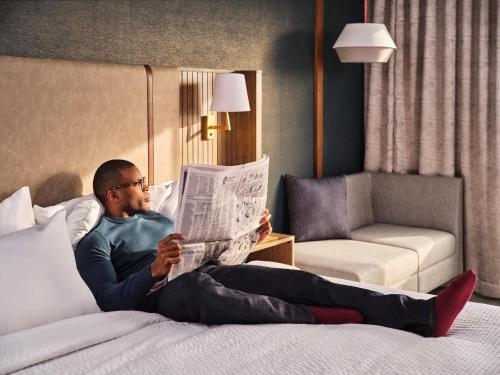 a man sitting on a bed reading a newspaper at Holiday Inn Chicago O'Hare - Rosemont, an IHG Hotel in Rosemont
