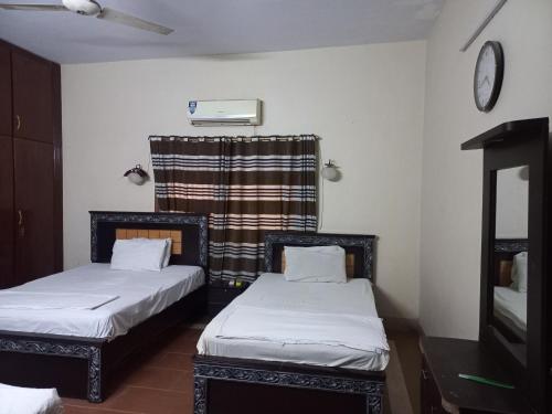 Habitación con 2 camas y reloj en la pared en Al Rehman guest hous, en Hyderabad