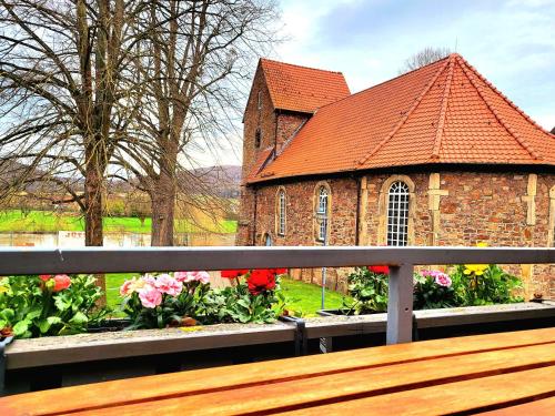 een houten bankje voor een kerk met bloemen bij Gästehaus am Weser-Radweg in Hannoversch Münden