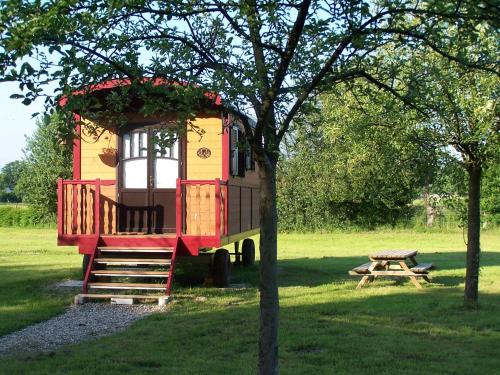 a tree house with a picnic table in a field at Les Roulottes de la Risle in Calleville