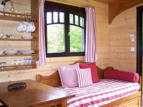a bench in a log cabin with a table and a window at Les Roulottes de la Risle in Calleville
