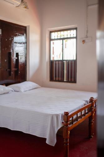a bedroom with a large white bed with a window at Kuttanad Kayak Club by Lexstays in Alleppey