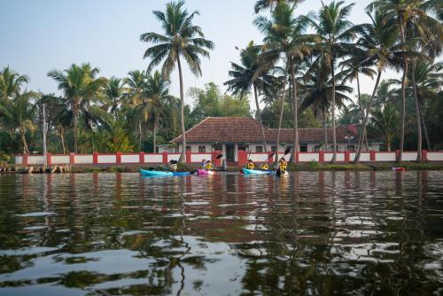 people kayaking on the water in front of a house at Kuttanad Kayak Club by Lexstays in Alleppey