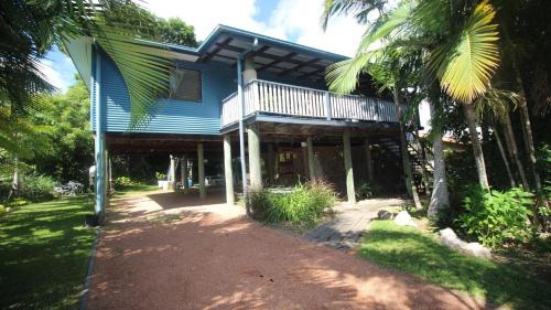 a blue house with a porch and palm trees at Magnetic Mango Escape in Horseshoe Bay