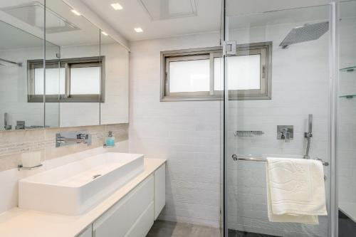 ein weißes Bad mit einem Waschbecken und einer Dusche in der Unterkunft Modern black & white by SeaU TLV in Tel Aviv