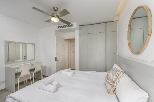 ein weißes Schlafzimmer mit einem Bett und einem Spiegel in der Unterkunft Modern black & white by SeaU TLV in Tel Aviv