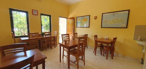 um restaurante com mesas e cadeiras de madeira numa sala em Whiterose Guesthouse em Senggigi