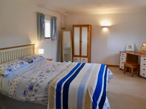a bedroom with a bed with a blue and white blanket at The Cowshed in Blofield
