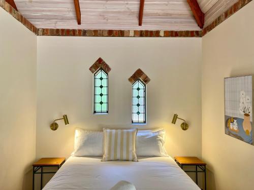 Waterfall Cottages في مارغريت ريفر: غرفة نوم مع سرير مع نافذتين على الحائط