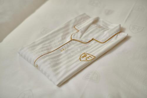 The Royal Park Hotel Hiroshima Riverside في هيروشيما: قميص ابيض عليه شعار ذهبي