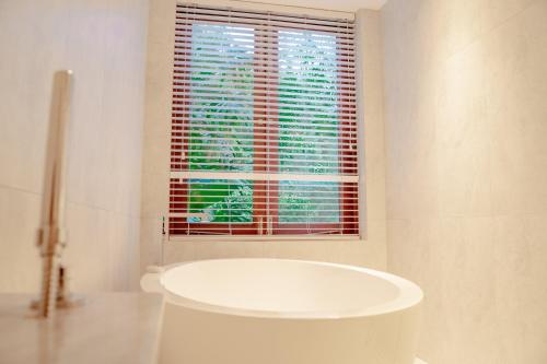 uma casa de banho com uma banheira branca em frente a uma janela em Lily Pod em Panadura