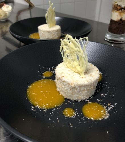 two plates of food on a black plate with yellow sauce at Logis Hotel Beaudon in Pierrefonds