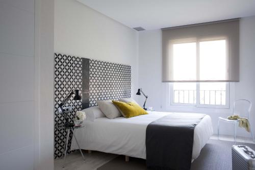 a white bedroom with a large bed and a window at Eric Vökel Boutique Apartments - Gran Vía Suites in Barcelona