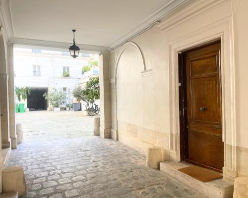 un couloir vide avec une porte en bois dans un bâtiment dans l'établissement Bohemian Flat - Lovely Marais, à Paris