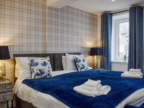 a bedroom with a blue bed with towels on it at The Hideaway in Crieff