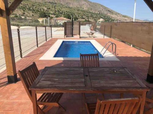 una mesa de madera y sillas junto a una piscina en Casa Cueva en Entorno Tranquilo., en Murcia